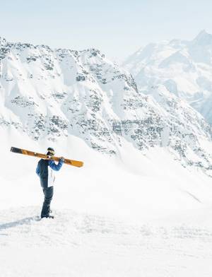 Homme tenant ses skis et contemplant la montagne